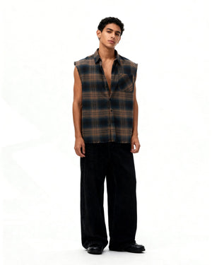 Man wearing a plaid sleeveless shirt and black pants on a white background