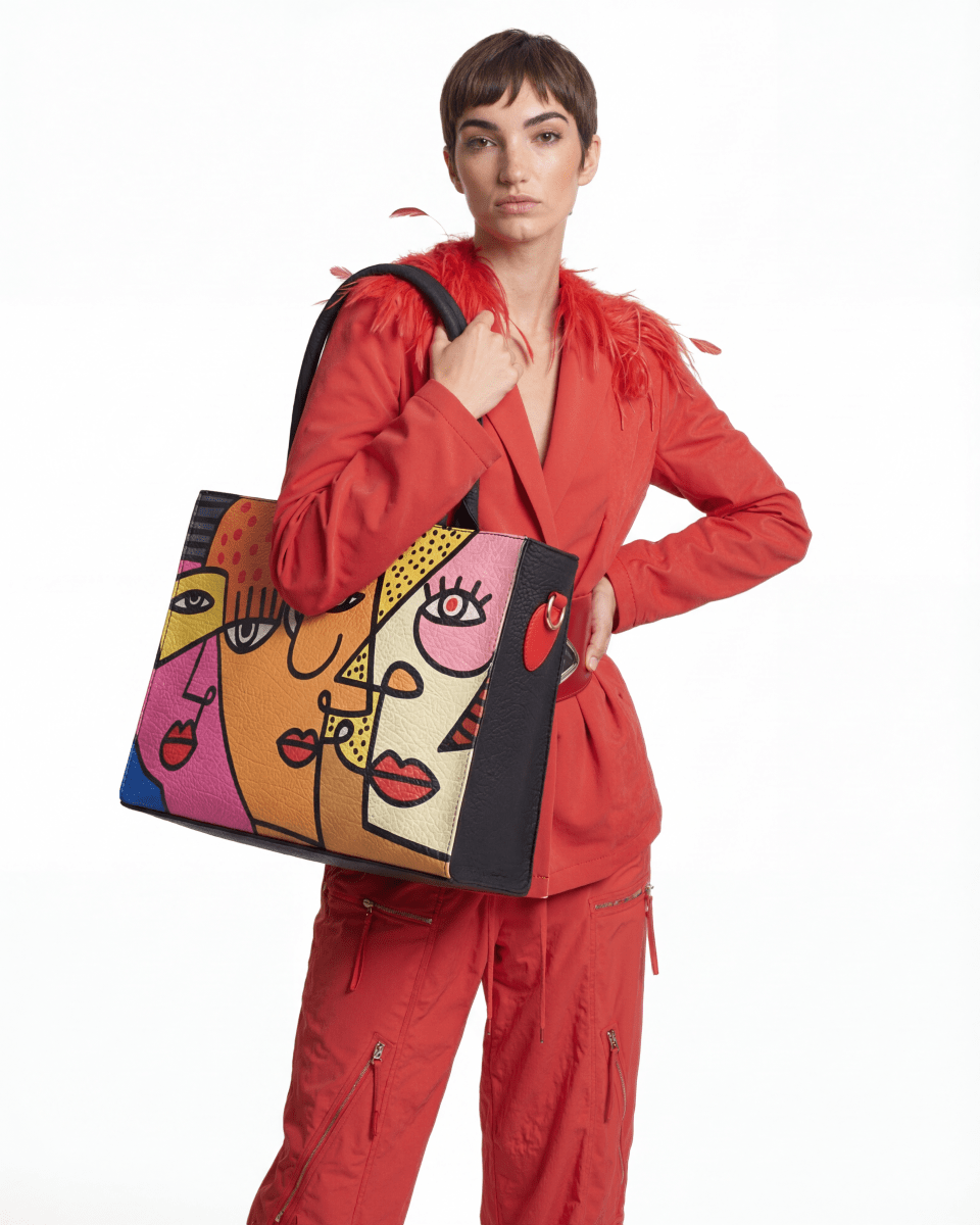 Close-up of a Woman holding FETTI Faces OG tote bag against a gray background